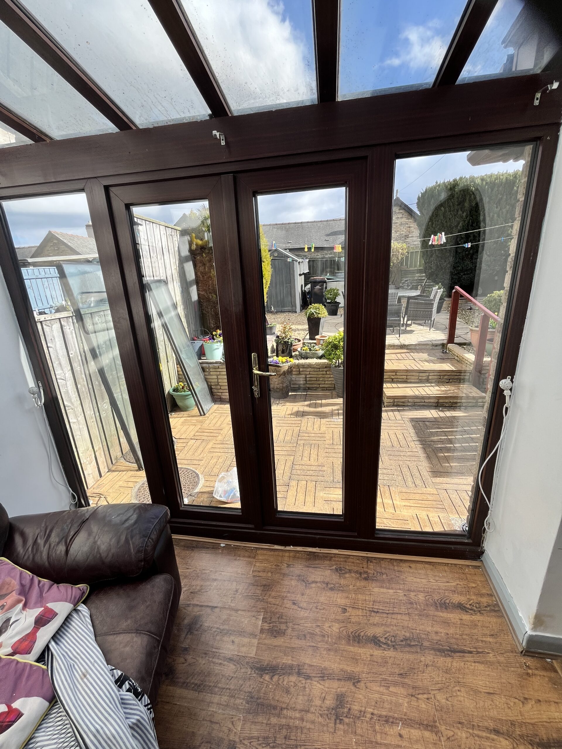 Brown French doors opening onto a conservatory